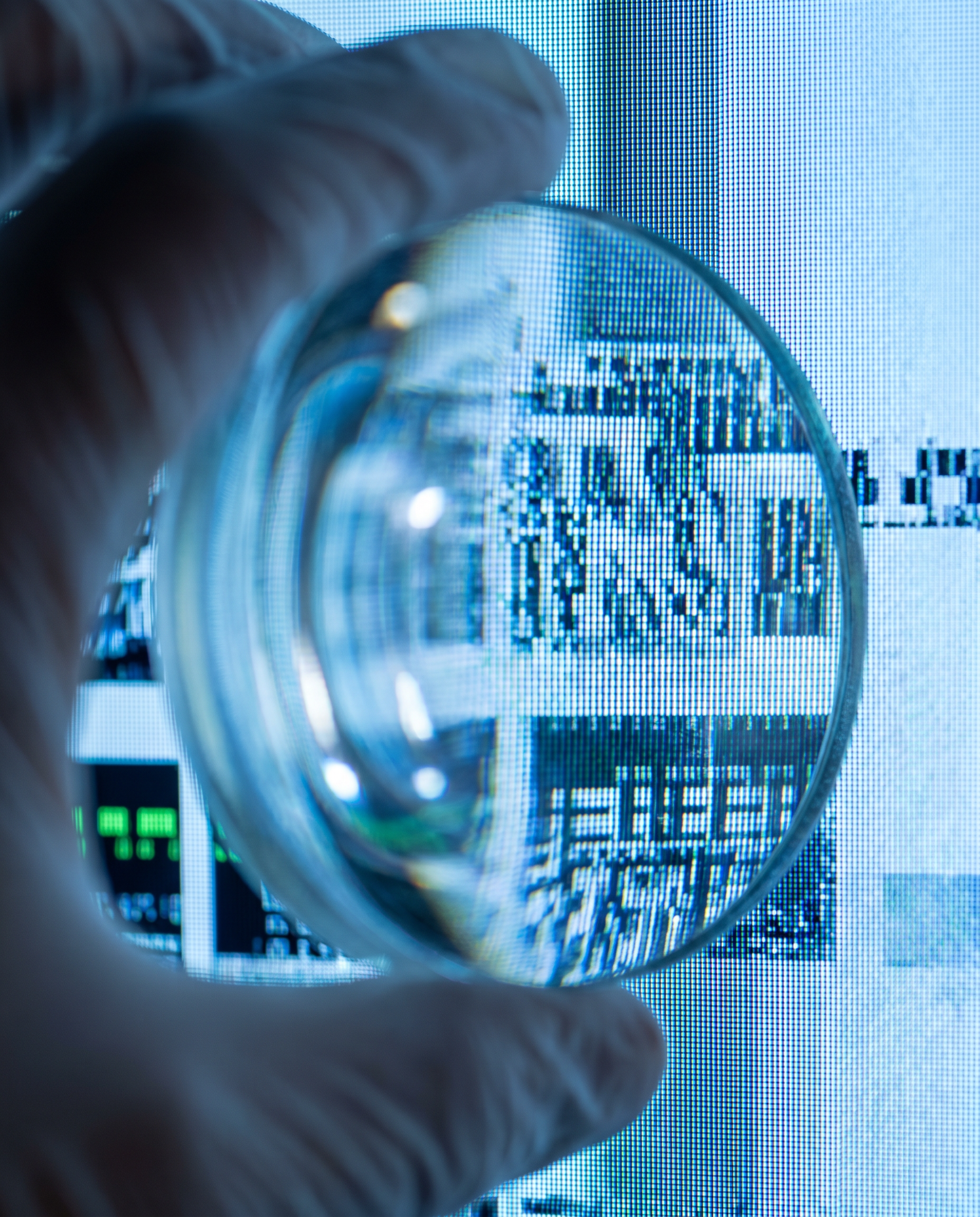 Photorealistic editorial photograph: dramatic macro close-up of computer screen pixels showing AI-generated text with visible repetitive phrase patterns, magnifying glass held by human hand in foregro