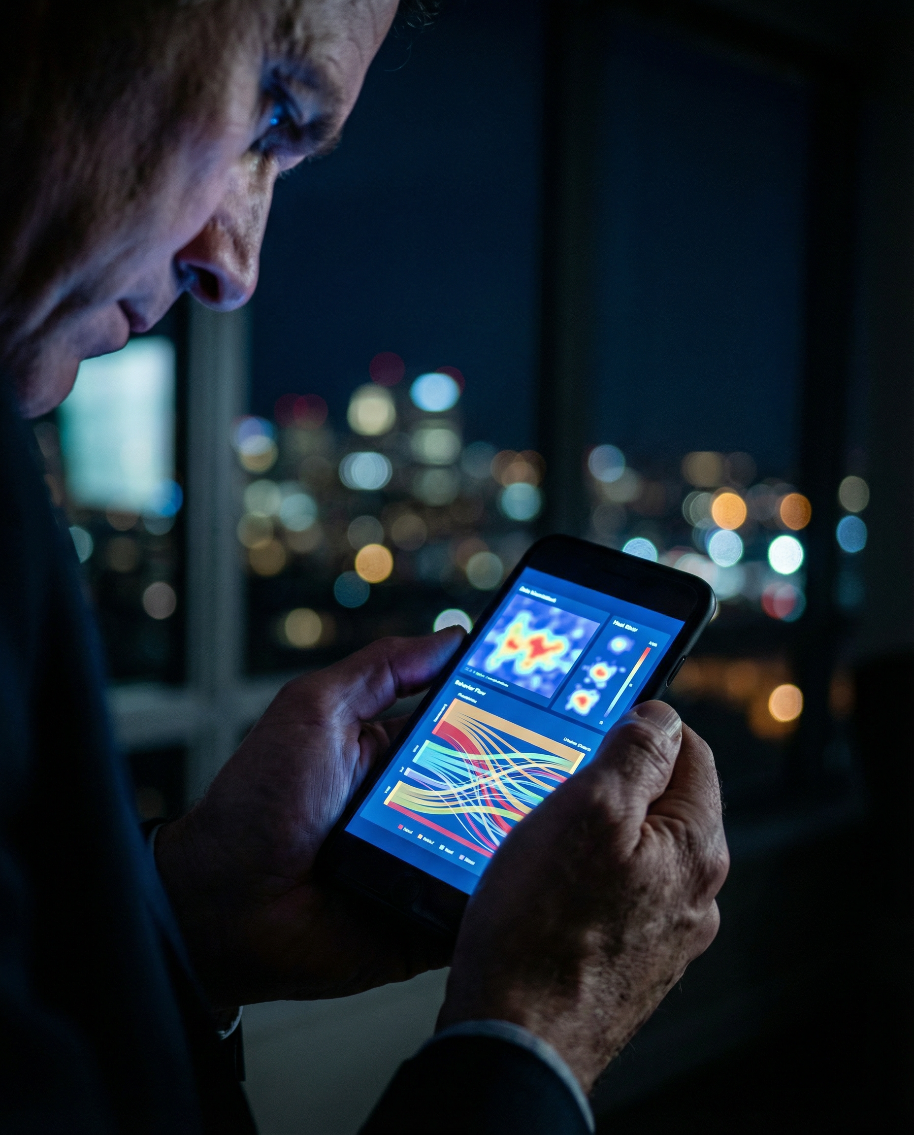 Photorealistic editorial photograph: tight close-up of smartphone screen held in businessman's hands showing predictive analytics dashboard with customer journey heat maps and behavior patterns, shot